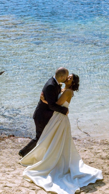 Groom kissing bride lake side